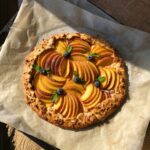 Delicious homemade peach galette with blueberries on parchment paper. Perfect summer dessert in natural light.